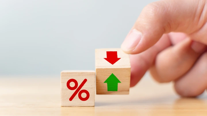 Cube en bois avec symbole pourcentage et flèches illustrant la hausse et la baisse des taux de crédit immobilier
